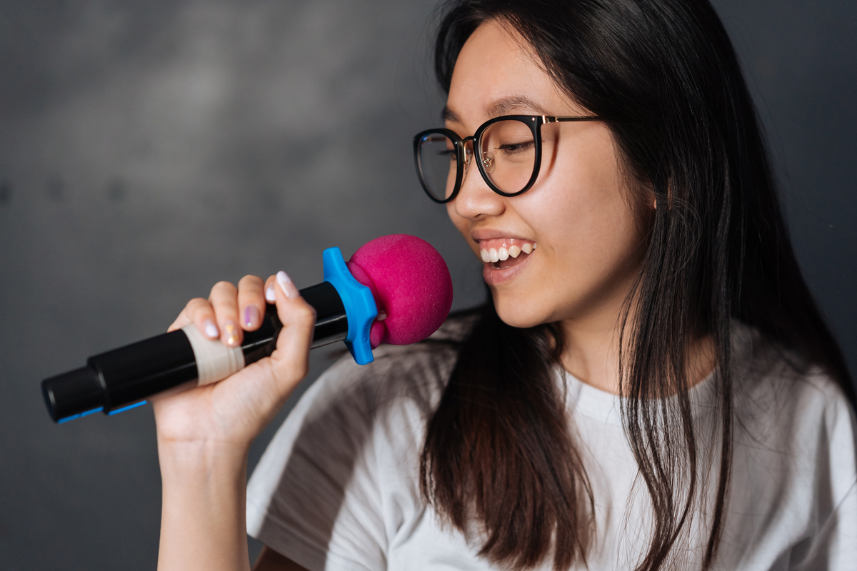 Young Woman in Black Eyeglasses using a Microphone 